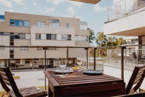 una mesa de madera con 2 copas de vino en el balcón en New Exclusive 2BD apartment by the sea en Saulkrasti