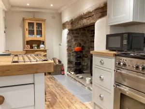 a kitchen with a stove and a stone wall at The Little Rose in Lyme Regis