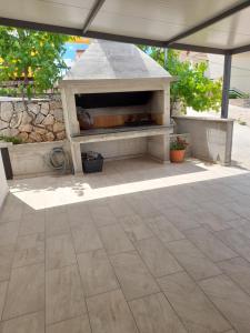 a patio with a stone fireplace under a roof at Apartmani Petra in Primošten