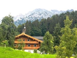 une maison en bois sur une colline avec des montagnes en arrière-plan dans l'établissement Trattenbachhof, à Scheffau am Wilden Kaiser