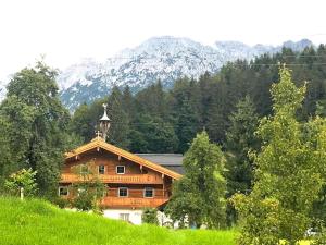 drewniany dom na wzgórzu z górami w tle w obiekcie Trattenbachhof w mieście Scheffau am Wilden Kaiser