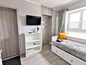 a bedroom with a bed and a tv on the wall at Apartamenty Fińska Gdynia in Gdynia