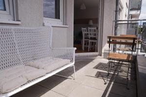 um banco branco numa varanda com uma mesa e cadeiras em FULL HOUSE Studios - KornhausPremium Apartment - Balkon, WiFi em Dessau