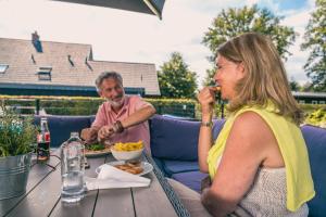 EuroParcs Reestervallei في IJhorst: يجلس رجل وامرأة على طاولة لتناول الطعام