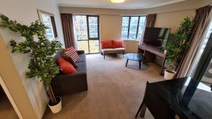 a living room with a couch and a television and plants at 2BR 2Bath L4 Executive Apartment, in City Centre in Canberra