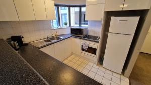 a kitchen with white cabinets and a sink and a refrigerator at 2BR 2Bath L4 Executive Apartment, in City Centre in Canberra