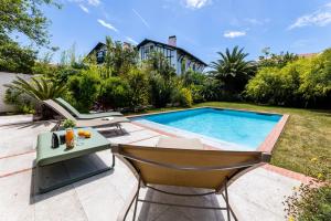 um quintal com uma piscina, uma mesa e cadeiras em LEONIE KEYWEEK Villa close to the Lighthouse and Biarritz's Golf course em Biarritz