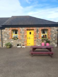 a brick house with a yellow door and a picnic table at Slane Farm Hostel, Cottages and Camping in Slane