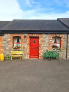 a brick building with a red door and two benches at Slane Farm Hostel, Cottages and Camping in Slane