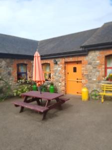 a picnic table with an umbrella in front of a building at Slane Farm Hostel, Cottages and Camping in Slane