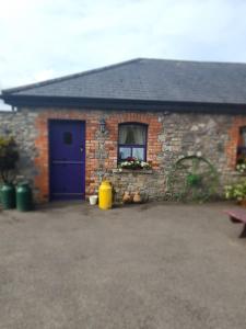 a brick house with a blue door and a window at Slane Farm Hostel, Cottages and Camping in Slane