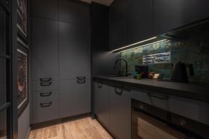 a kitchen with black cabinets and a sink at Coffee Apartment Gdynia in Gdynia +22 photos