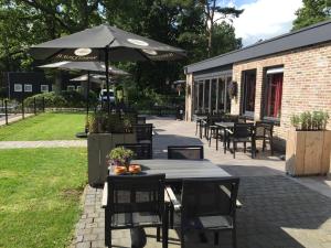 un patio con tavoli, sedie e ombrellone di EuroParcs Reestervallei a IJhorst