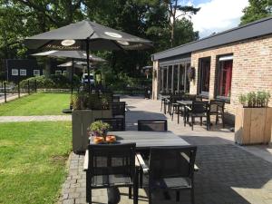 a patio with tables and chairs and an umbrella at EuroParcs Reestervallei in IJhorst