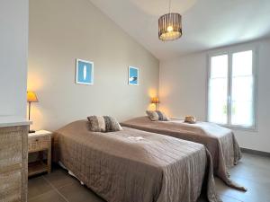 1 dormitorio con 2 camas y ventana en Le Clos des Vieux Moulins, en La Flotte