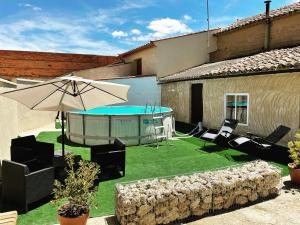 a patio with an umbrella and a swimming pool at El desván de Bruno in Villalobos