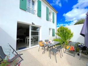 a patio with a table and chairs in front of a building at Le Clos des Vieux Moulins in La Flotte
