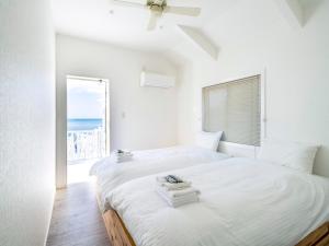 Un dormitorio blanco con dos camas y una ventana. en サンセットリゾート　かぬたん, en Gushiken