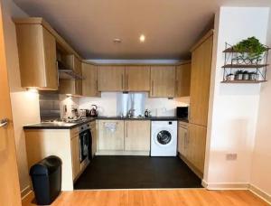 a kitchen with wooden cabinets and a washer and dryer at SECC&HYDRO BeAUTIFUL 2BR APARTMENT WITH FREE PARKING in Glasgow