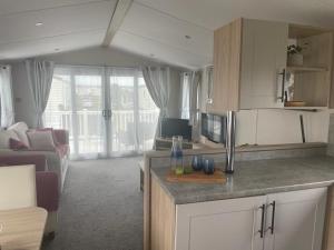 a kitchen and living room with a couch and a tv at Dune View Caravan in Lossiemouth