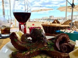 a plate with an octopus on a table with a glass of wine at Virginia in Siracusa
