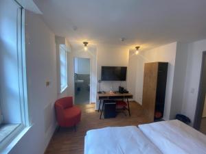 Schlafzimmer mit einem Bett und einem Schreibtisch mit einem roten Stuhl in der Unterkunft Altstadthotel Alt & Jung in Regensburg
