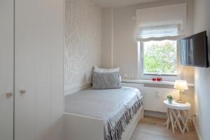 Cette petite chambre blanche dispose d'un lit et d'une fenêtre. dans l'établissement Schneckenhüs, à Westerland