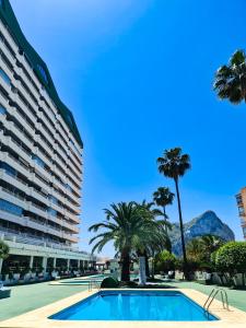 basen z palmami i duży budynek w obiekcie AVANOA - Esmeralda Calpe w mieście Calpe