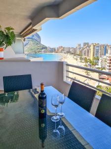stół z 2 kieliszkami do wina na balkonie z plażą w obiekcie AVANOA - Esmeralda Calpe w mieście Calpe