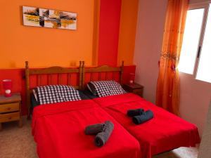 トレビエハにあるApartamento Ibanez, casa 119のベッドルーム1室(ベッド2台、赤いシーツ、スリッパ付)