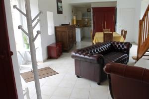 a living room with a leather couch and a kitchen at La Maison de Lésa in Kerandraou