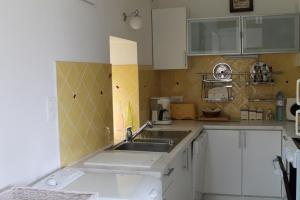 una cocina con armarios blancos y fregadero en La Maison de Lésa en Kerandraou