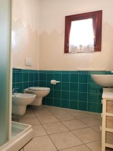 une salle de bains verte avec deux toilettes et une fenêtre dans l'établissement Case Vacanze San Silvestro, à Budoni