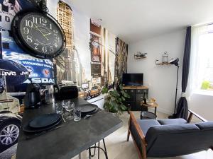 ein Wohnzimmer mit einem Tisch und einer Uhr an der Wand in der Unterkunft Le petit atelier - Studio - WIFI - Coeur de ville - Parking in Pont-lʼAbbé
