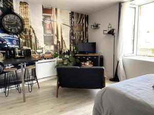 a bedroom with a bed and a desk and a clock at Le petit atelier - Studio - WIFI - Coeur de ville - Parking in Pont-lʼAbbé