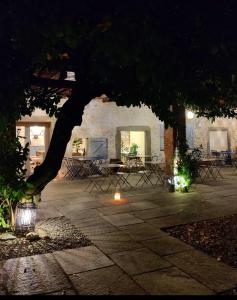 un patio con mesas y un árbol por la noche en Dandelion Como Suites & Park, en Villa Guardia