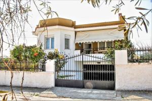 a white house with a gate in front of it at Myrsini' s House in Nea Peramos