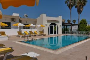 a pool with chairs and umbrellas next to a building at Katherina's Studios in Kefalos