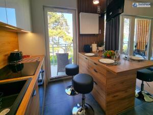 a kitchen with a counter with stools in it at 365PAM - Apartament LET'S SEA z widokiem na morze - BASEN, JACUZZI, SAUNA, SIŁOWNIA, STREFA CHILL, PARKING W CENIE in Gąski