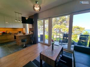 a living room with a table and a large window at 365PAM - Apartament LET'S SEA z widokiem na morze - BASEN, JACUZZI, SAUNA, SIŁOWNIA, STREFA CHILL, PARKING W CENIE in Gąski