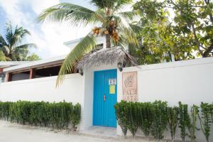 un edificio con una porta blu e una palma di Palm Gate Maldives a Thulusdhoo