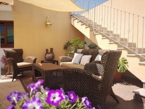 a patio with wicker chairs and a couch and stairs at Hotel Cala Mirto in Budoni