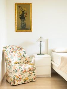 a bedroom with a floral chair next to a bed at Luminosa casetta per due in Bardolino