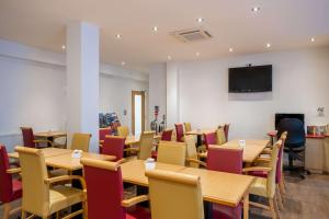 a dining room with tables and chairs and a tv at Comfort Inn Edgware Road in London