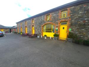 a building with yellow doors and benches in a parking lot at Slane Farm Hostel, Cottages and Camping in Slane