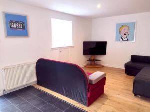 a living room with a couch and a television at Abbey House in Paisley