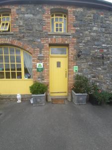 a yellow door on a brick building with two plants at Slane Farm Hostel, Cottages and Camping in Slane