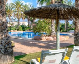 アリカンテにあるHotel Alicante Golfのスイミングプールの横に椅子とパラソルがあります。