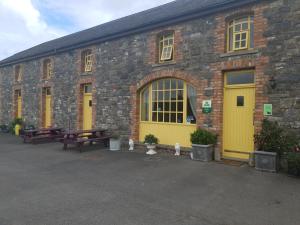 a brick building with yellow doors and benches at Slane Farm Hostel, Cottages and Camping in Slane