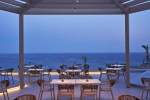 a restaurant with tables and chairs with the ocean in the background at Rodos Princess Beach Hotel in Kiotari